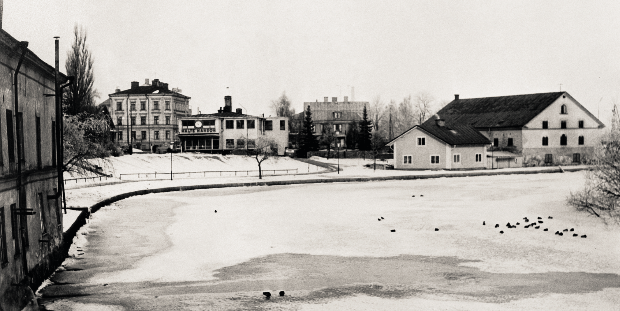 Svartvitt foto på byggnader som ligger läng Stångån